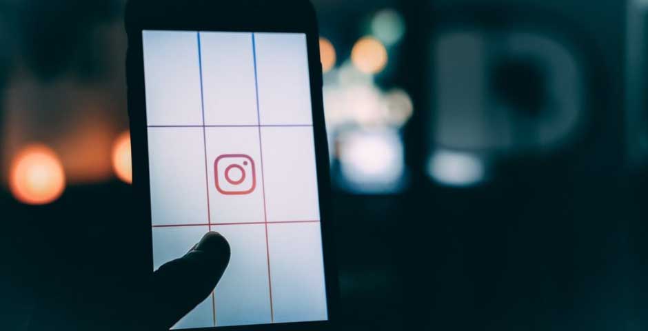 A phone in the dark showing the Instagram logo